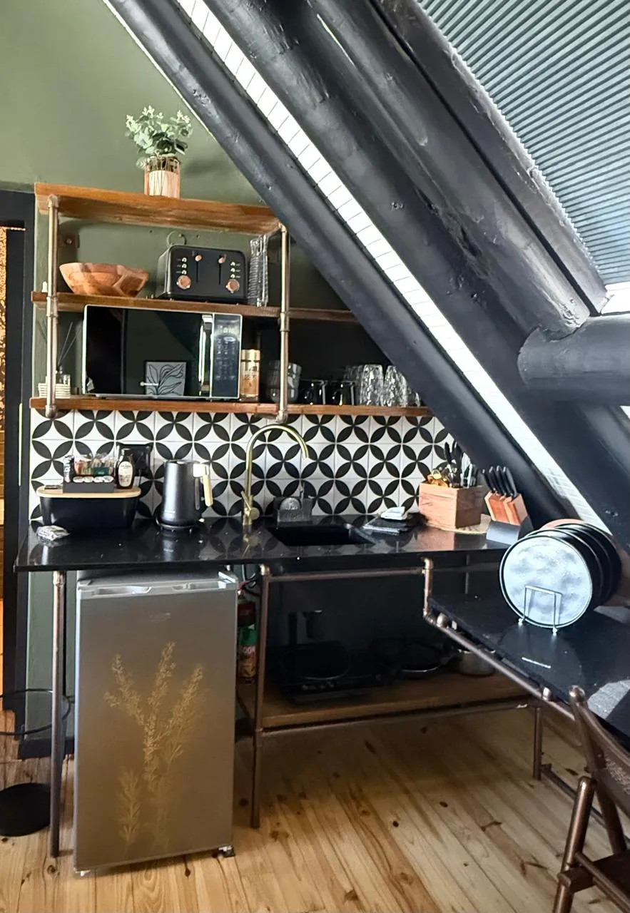 The fully equipped kitchenette with black granite worktops, geometric tiles and open shelving