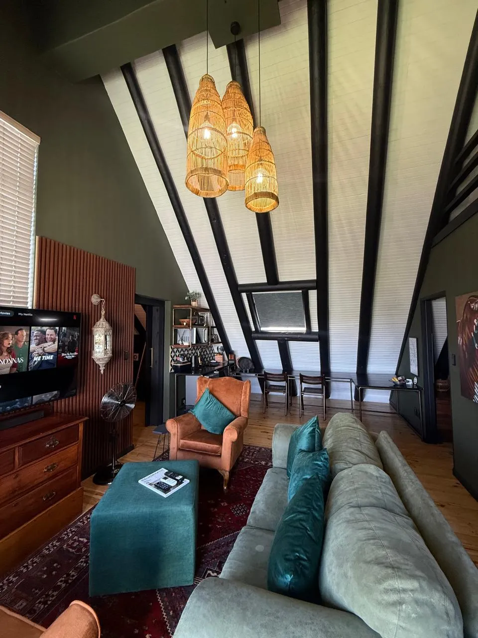 The open-plan living area beneath the A-frame ceiling, with wicker pendant lights and a velvet sofa