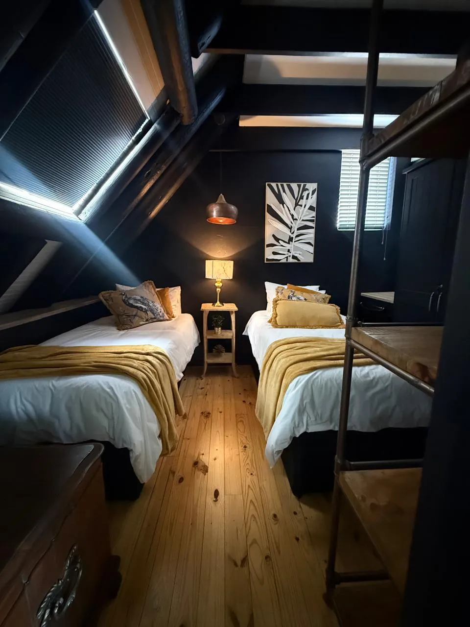 The twin bedroom with two single beds, dark navy walls, skylights and a loft ladder