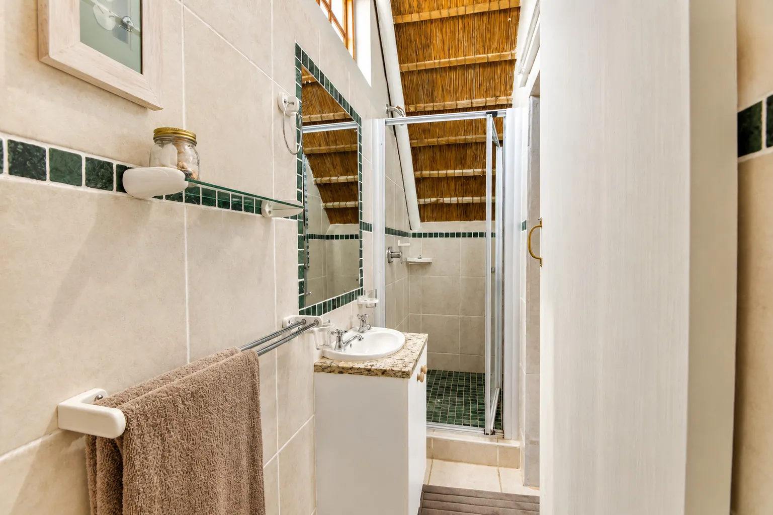 Berry Cottage's en-suite bathroom with a green-tiled shower beneath the thatch