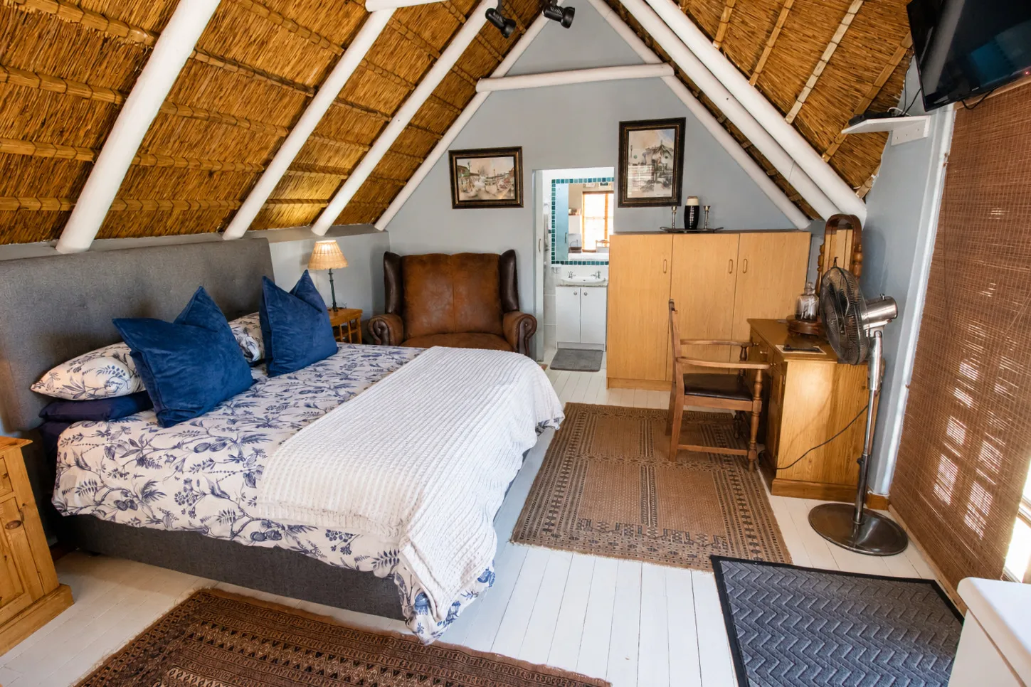 Berry Cottage's queen bed with a leather wingback armchair alongside