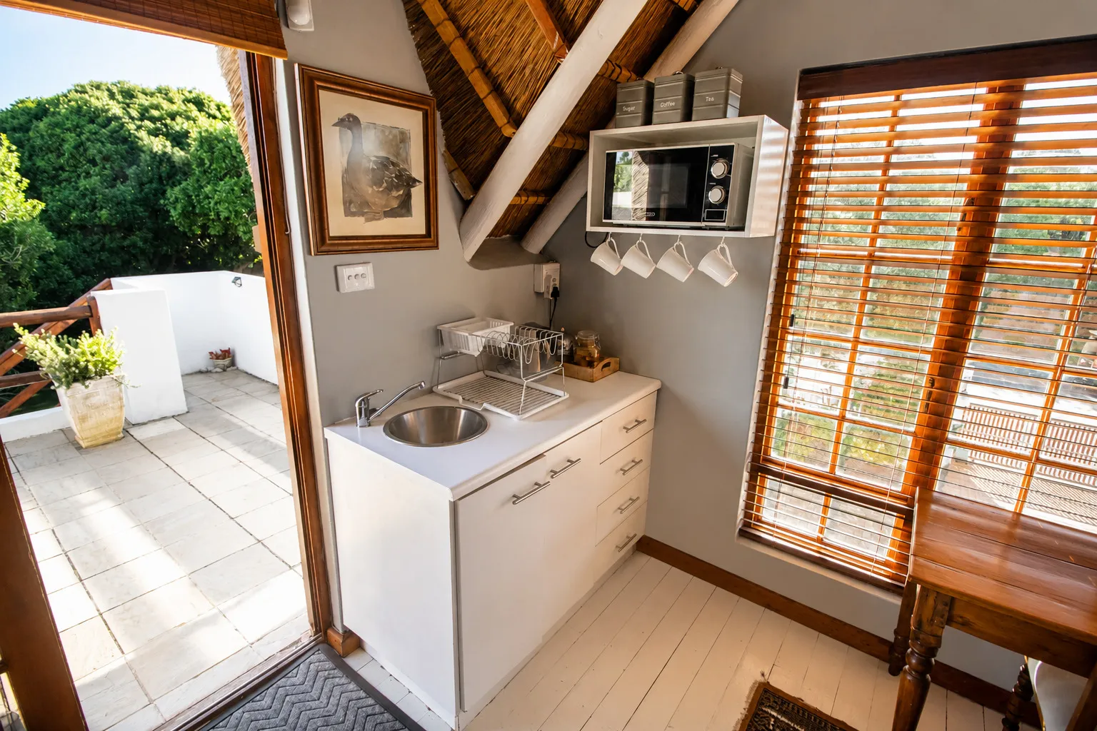 Berry Cottage's kitchenette with microwave and tea and coffee tray beside the open verandah door