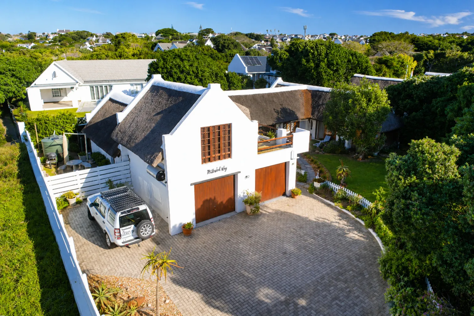 Aerial view of Milkwood Way, the thatched entrance, driveway and 'Milkwood Way' signage above the garage doors