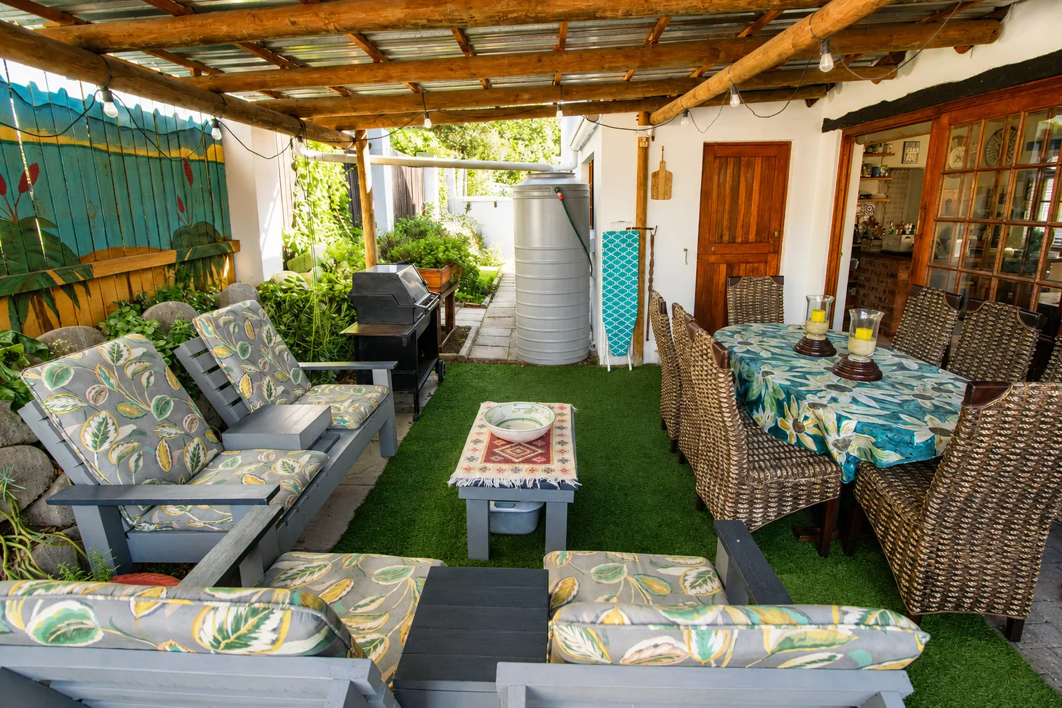 The braai patio set for dinner, with a wicker dining suite and the kitchen door beyond