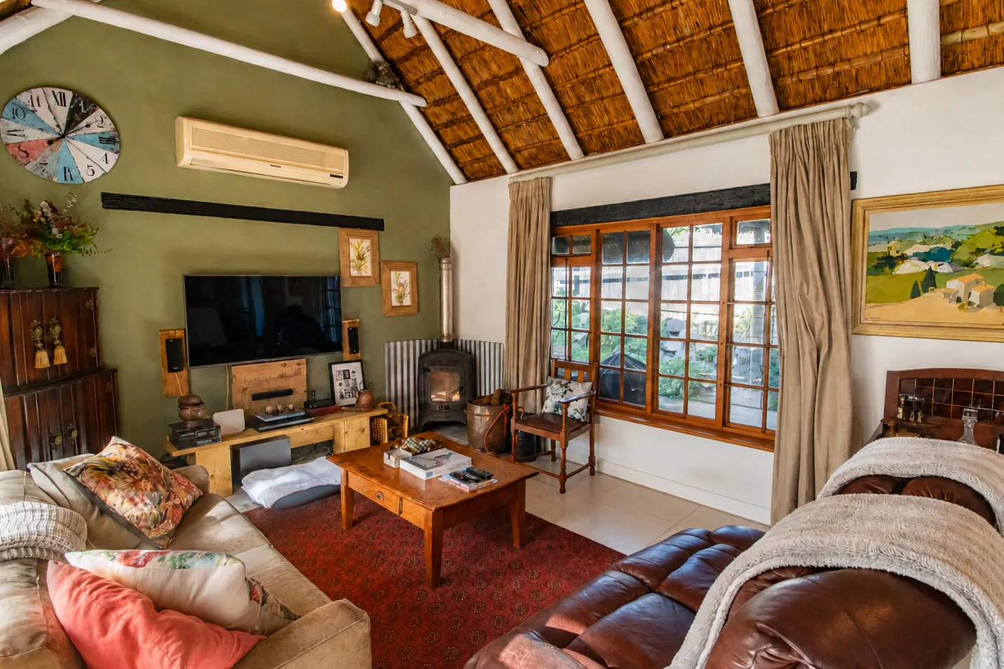 The lounge fireplace corner beneath the thatch, with a wood burner and armchair