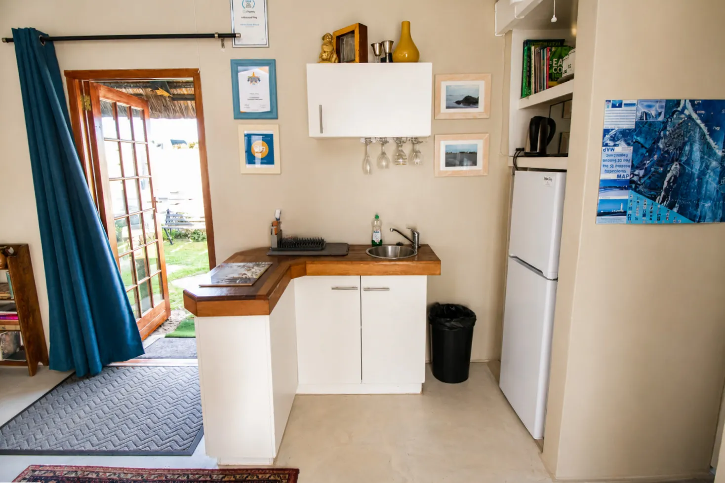 Milkwood Cottage's kitchen counter with sink, fridge-freezer and a view out to the garden