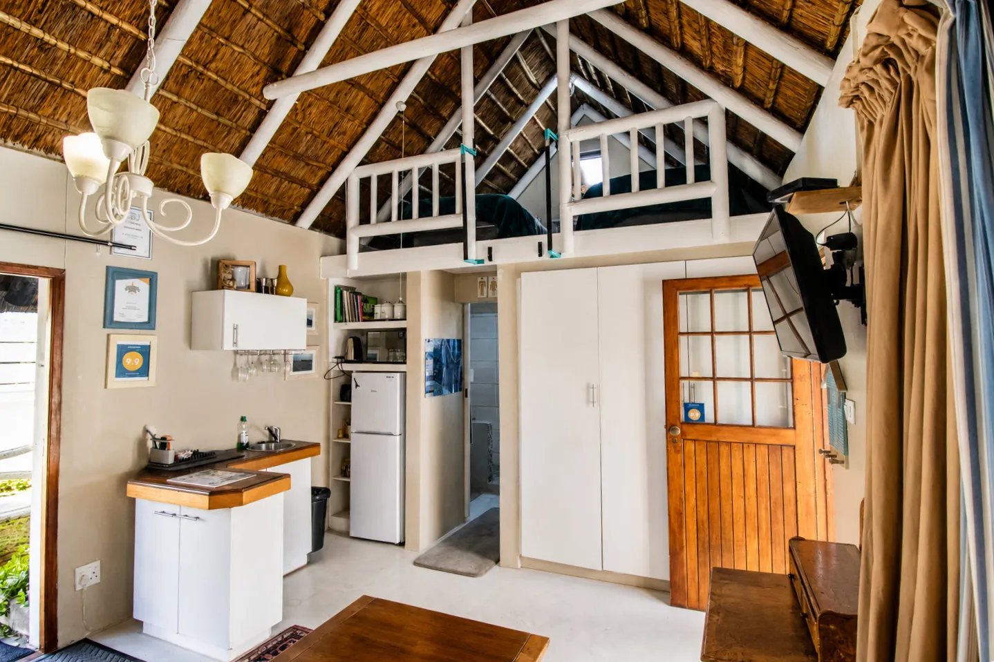 Milkwood Cottage's kitchenette and the loft above, reached by a step ladder beneath the thatch