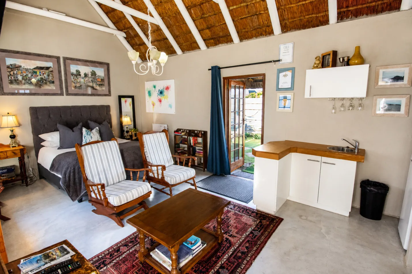 Milkwood Cottage's living area with the bed, bookshelf and kitchenette in one open-plan room