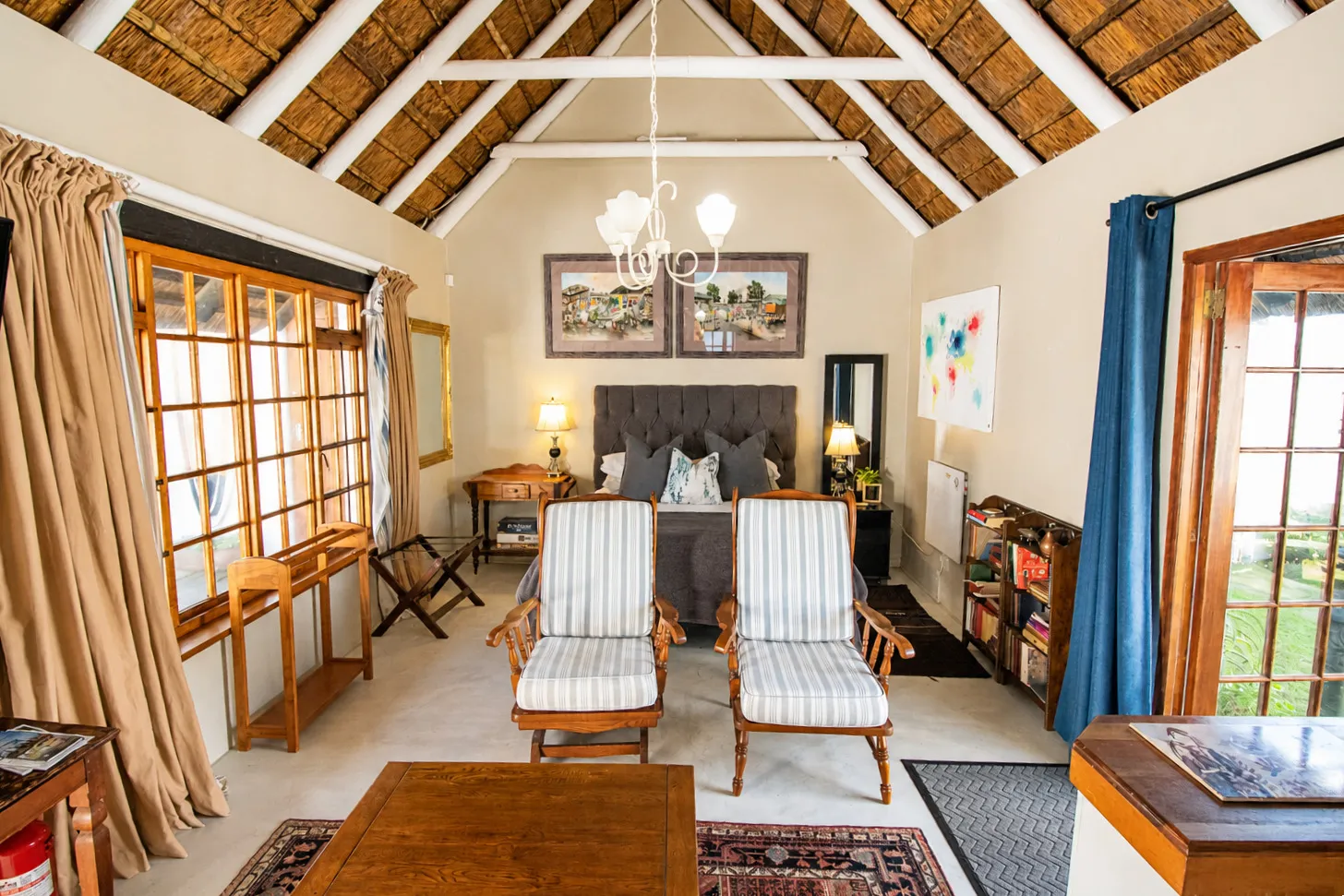 Milkwood Cottage's queen bed and armchairs, with the courtyard visible through the open door